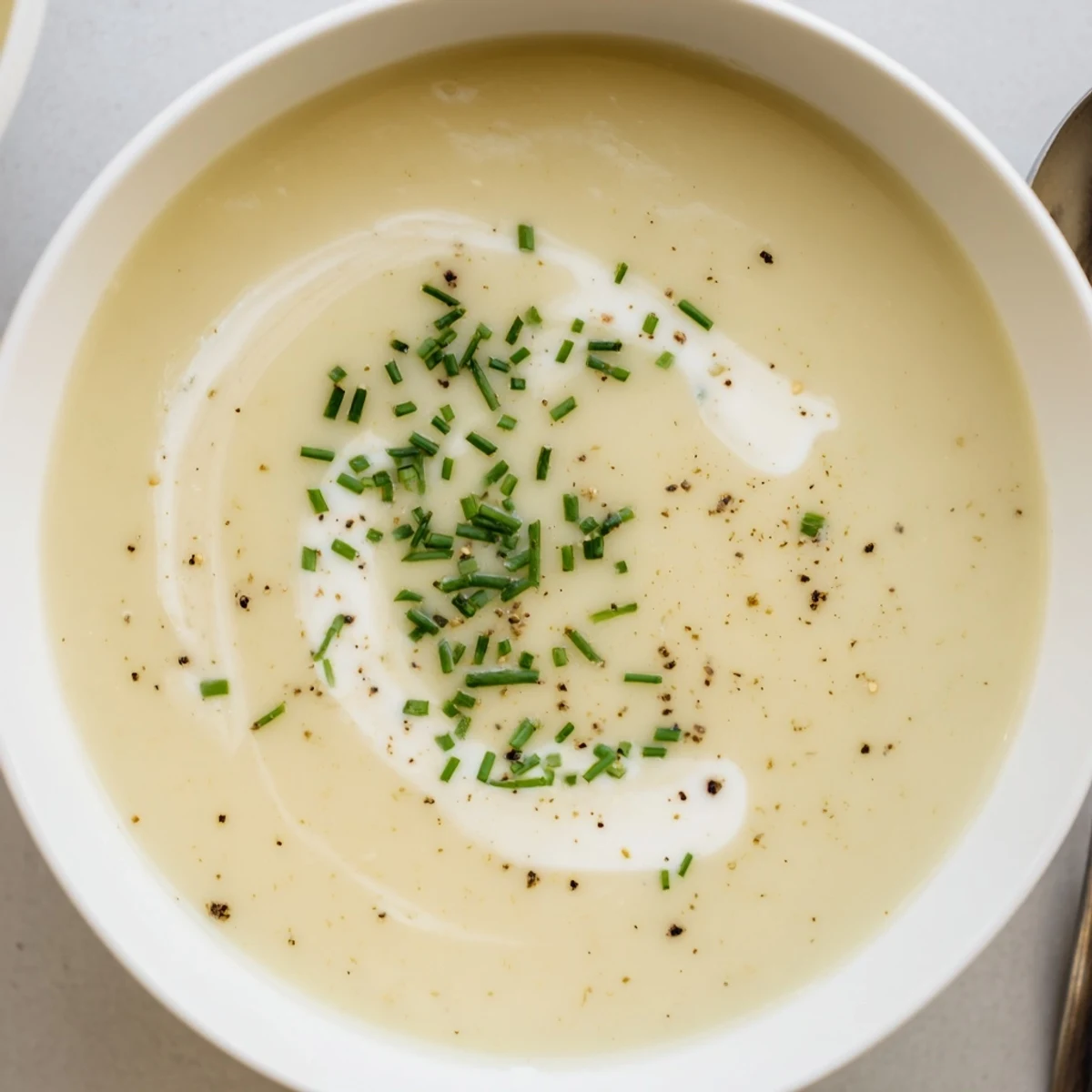 Freshly chopped chives top a warm bowl of Creamy Leek Soup with Potatoes, highlighting the comforting, velvety texture.