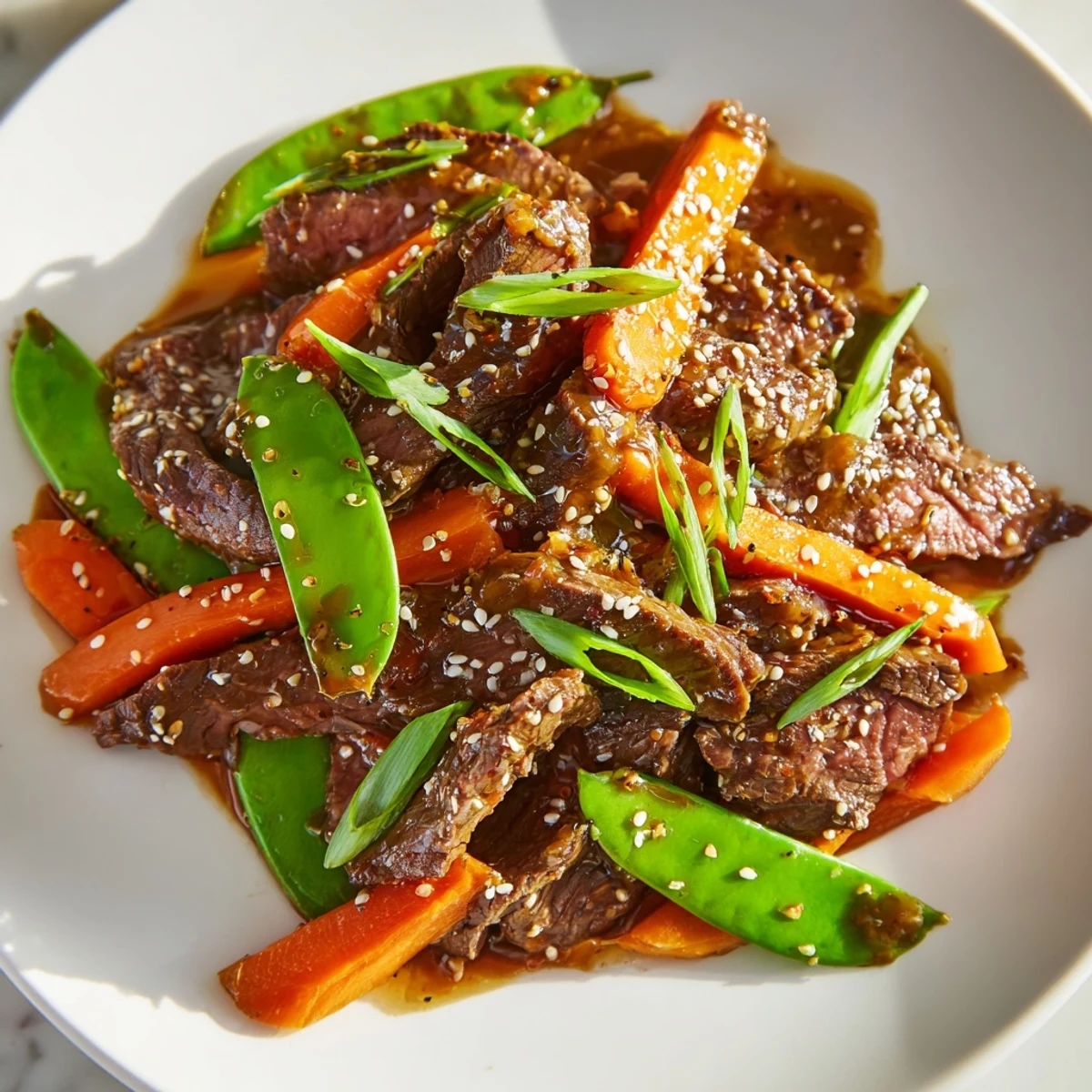 Beef Stir Fry with Snow Peas and Carrots glistens with a glossy, savory sauce, tender beef slices, and crisp vegetables served hot.