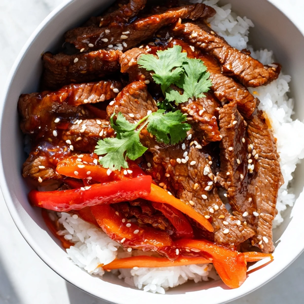 Steamed rice topped with Spicy Beef Bowl featuring tender beef strips, crisp bell peppers, and snap peas in a glossy sauce.