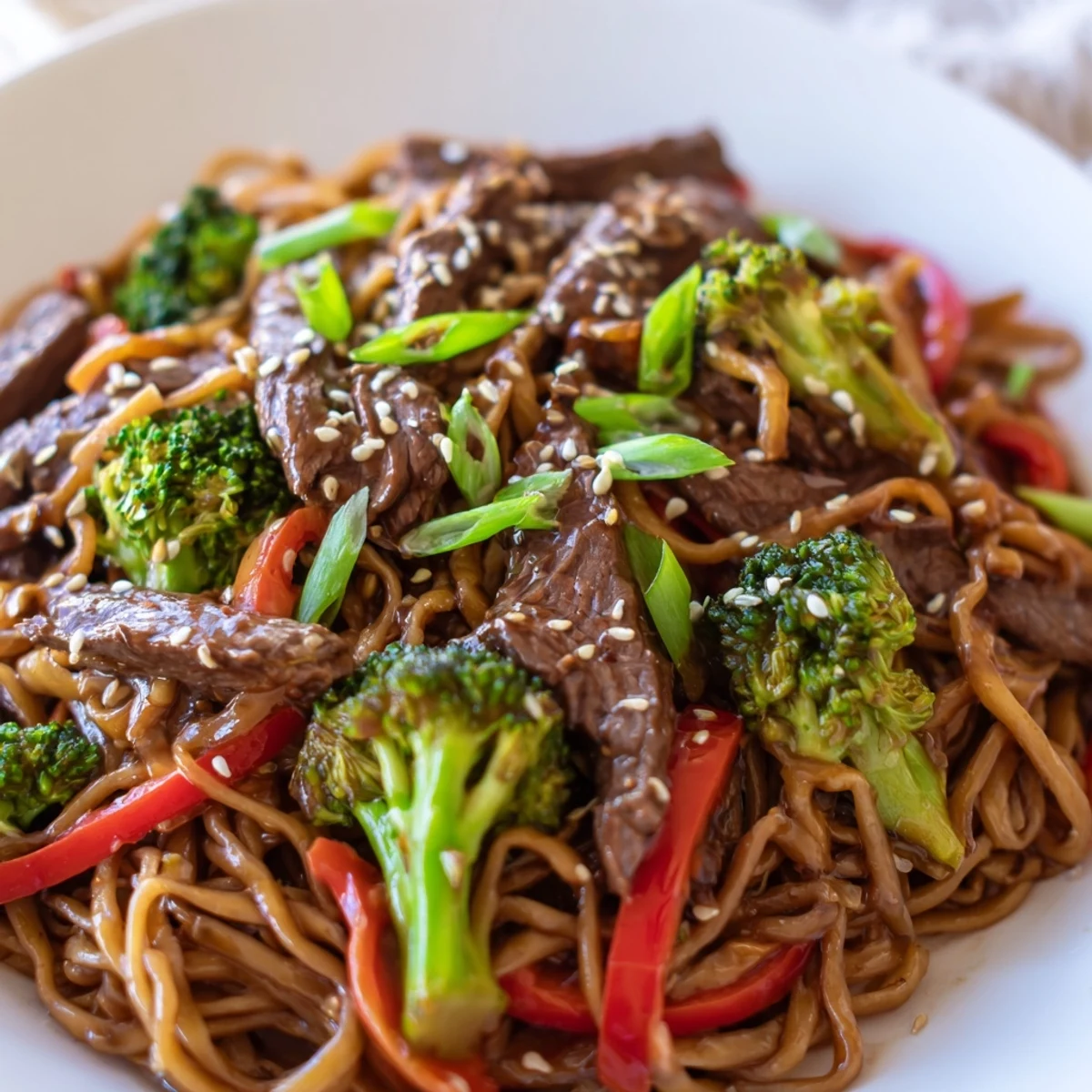 Beef and Broccoli Lo Mein with Sesame served from a wok, tossed with red bell pepper and green onions for dinner.