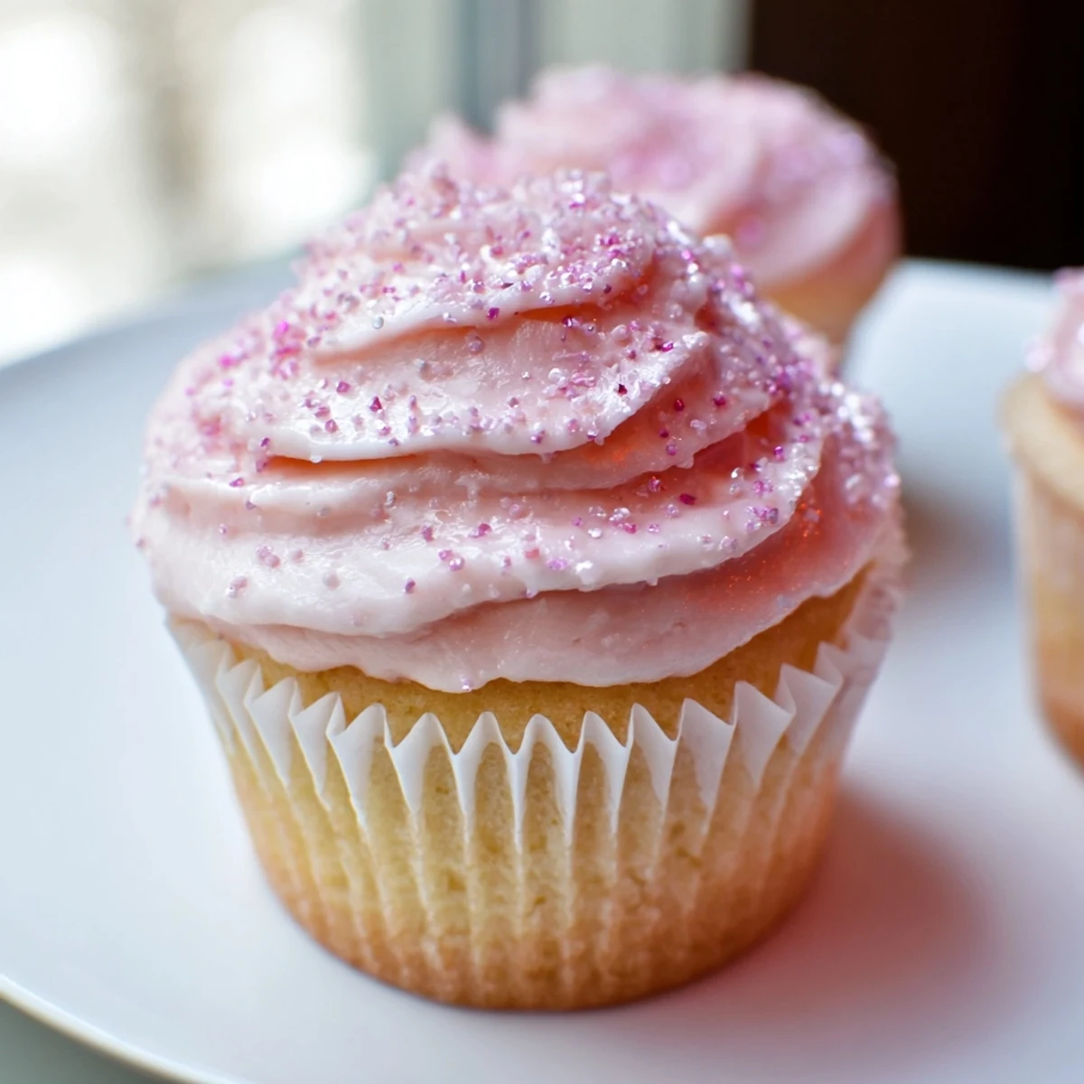 Close-up of Pink Champagne Cupcakes topped with glossy pink frosting and edible glitter, ready for a festive celebration.