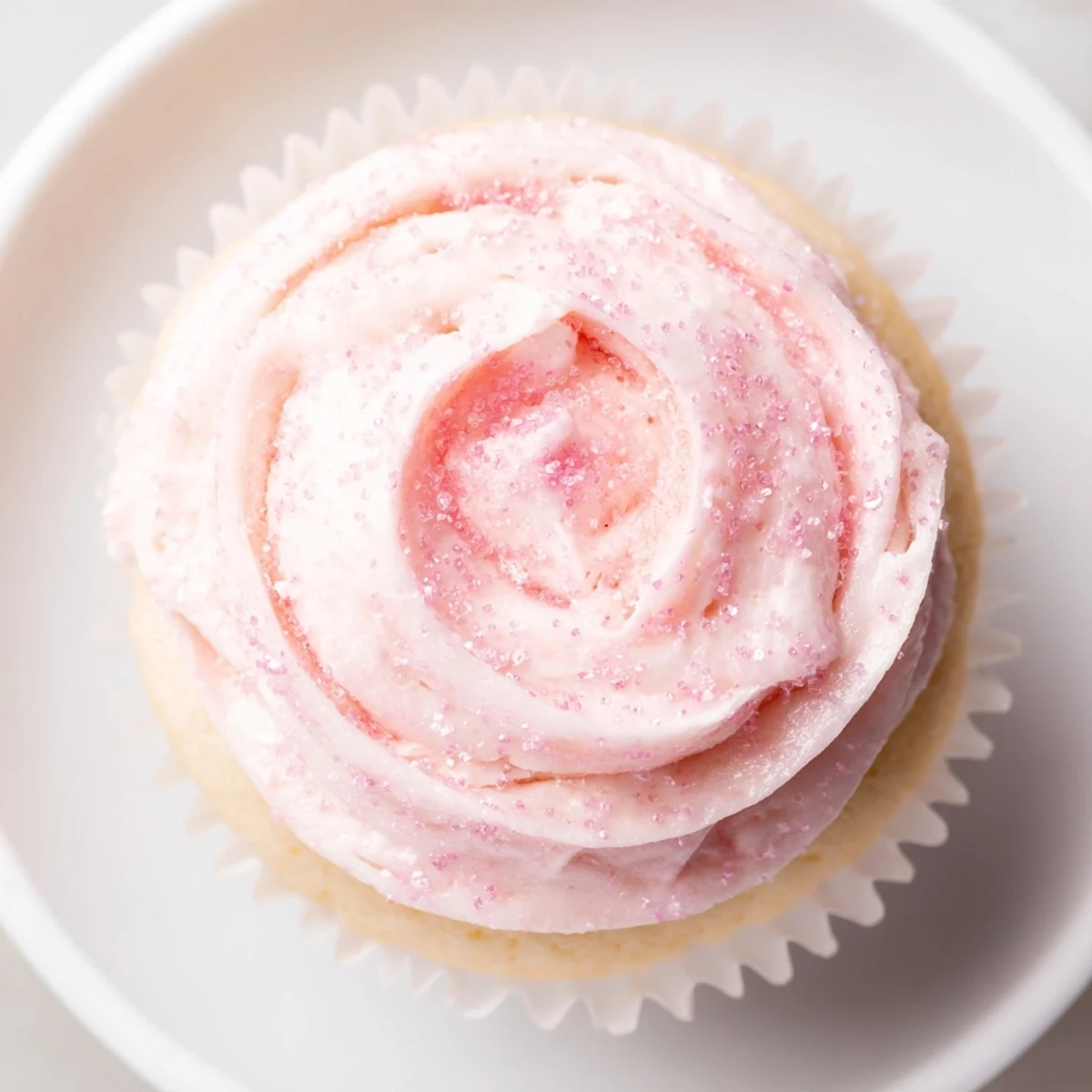 Freshly baked Pink Champagne Cupcakes cooled on a wire rack, with pink grape juice glaze and decorative sprinkles.