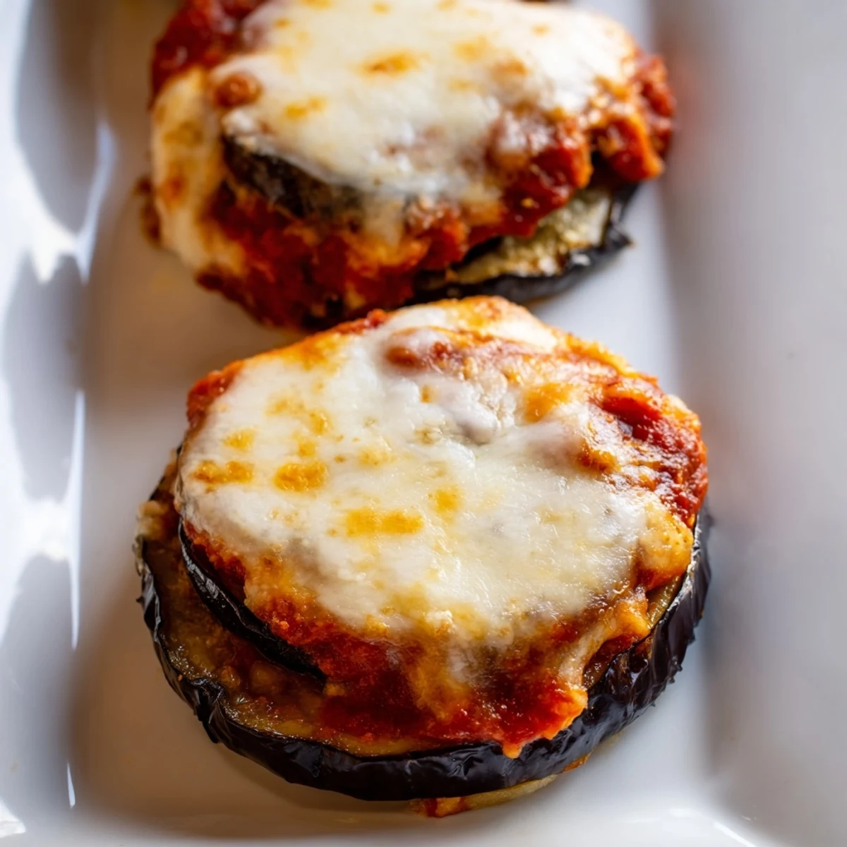 Slices of baked eggplant stacked with marinara sauce and bubbling mozzarella for a classic Vegetarian Eggplant Parmesan main dish.
