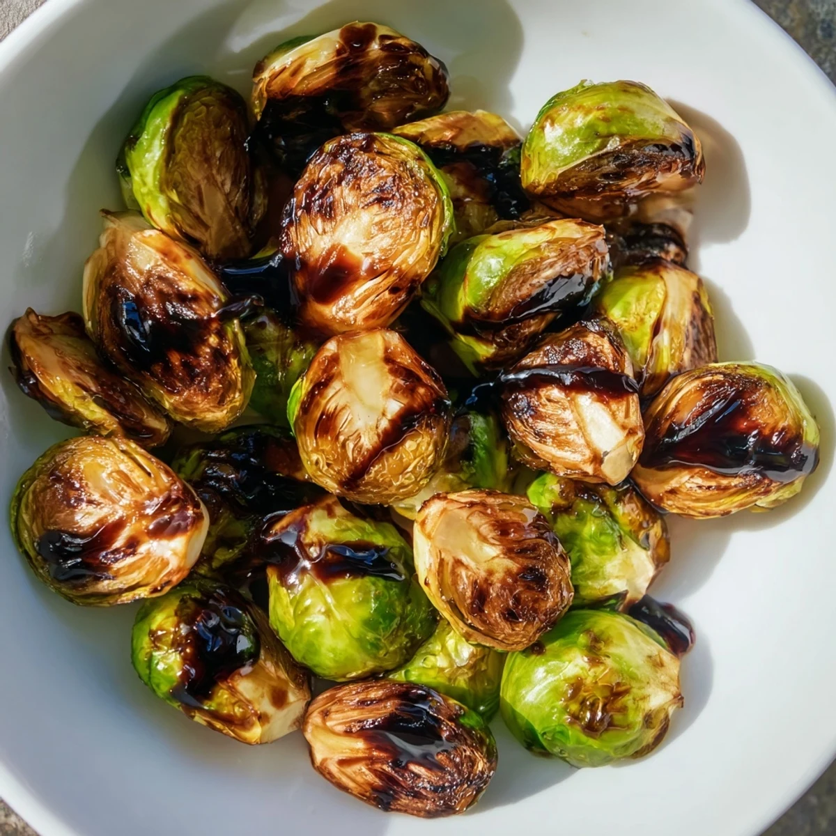 Close-up of Roasted Brussels Sprouts with Balsamic Glaze, showcasing tender green centers and a sweet, tangy reduction coating each half.