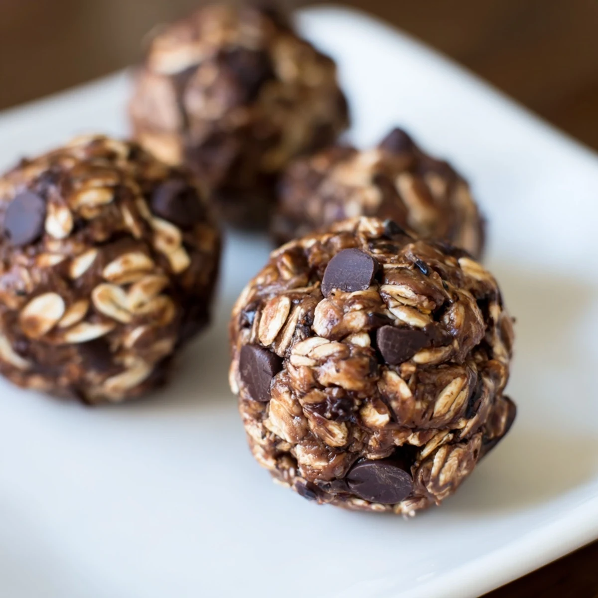 Ready-to-eat chocolate peanut butter energy balls sit on parchment with a busy morning spread.  