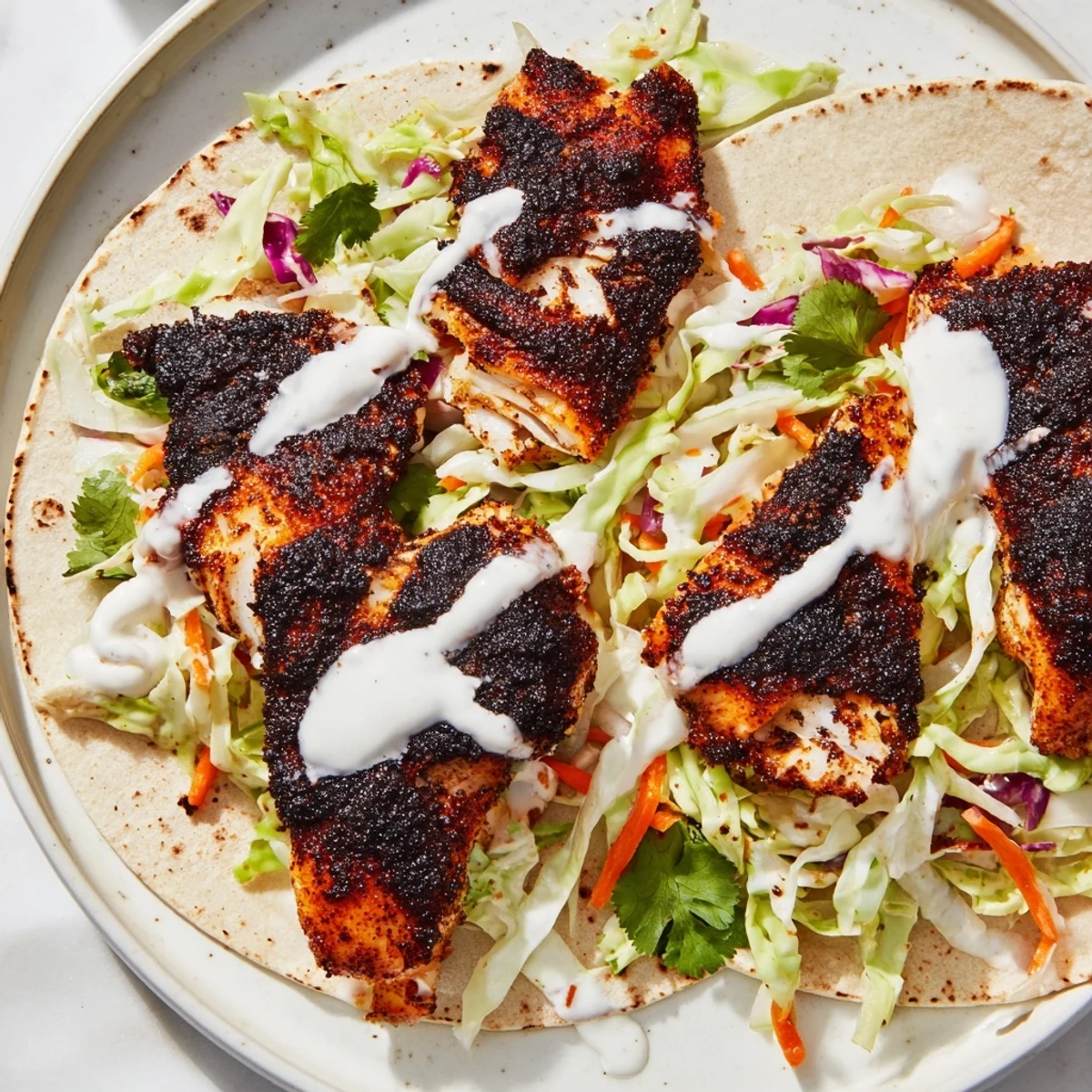 A skillet of blackened fish rests beside warm tortillas and zesty slaw for these tacos.