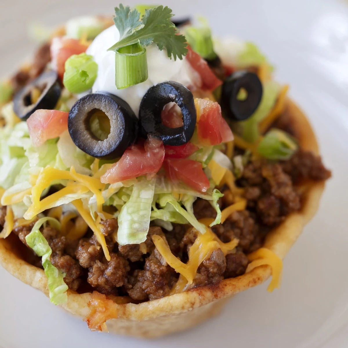 A close-up of golden, crispy baked Touchdown Taco Cups brimming with seasoned beef, layered with melted cheese, fresh lettuce, and bright diced tomatoes.  