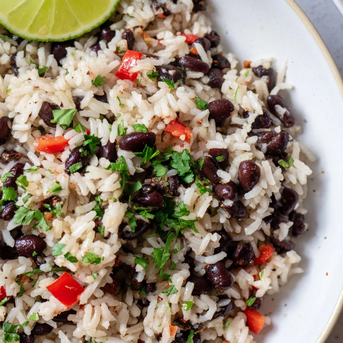 Golden Rice and Beans with Spices simmering in a pan, the vibrant red bell pepper and onion mixing with the spices.