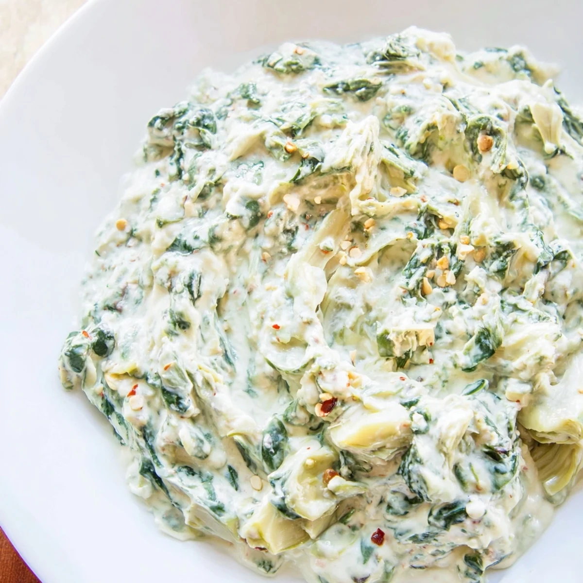 Creamy Spinach Dip with Artichokes and Cheese served warm from the oven, ready for dipping with crunchy crackers.