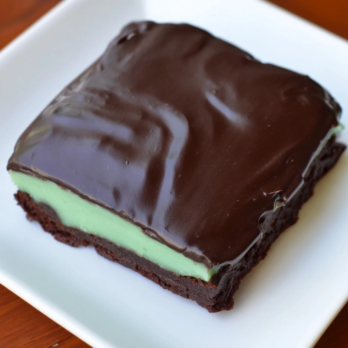 A close-up of stacked Green Mint Brownies with glossy chocolate glaze and a vibrant mint layer.