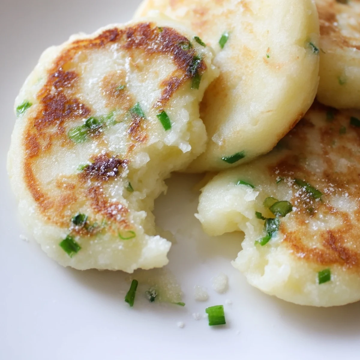 A close-up shows golden-brown Irish Potato Cakes with Scallions stacked high, ready to be enjoyed as a hearty breakfast or comforting side dish.