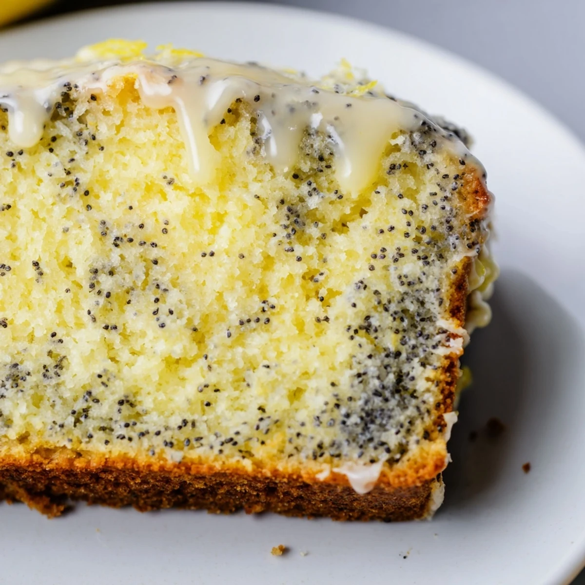 Golden-brown Lemon Poppy Seed Loaf cooling on a wire rack, topped with a generous drizzle of zesty lemon glaze catching the light.