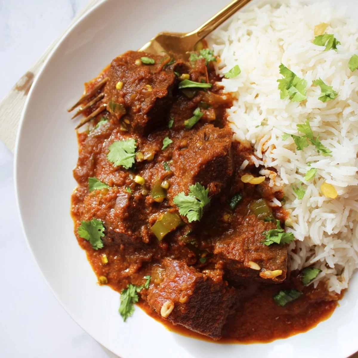 Spicy Beef Curry with Rice is served steaming in a rustic clay pot, garnished with fresh cilantro and a side of naan, perfect for a cozy weeknight dinner.