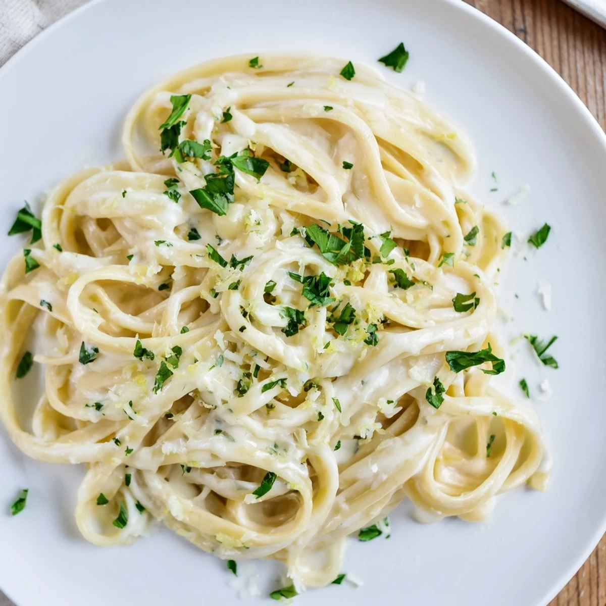 A close-up of Creamy Garlic Pasta with Fresh Herbs twirled on a fork, highlighting velvety sauce coating fettuccine.