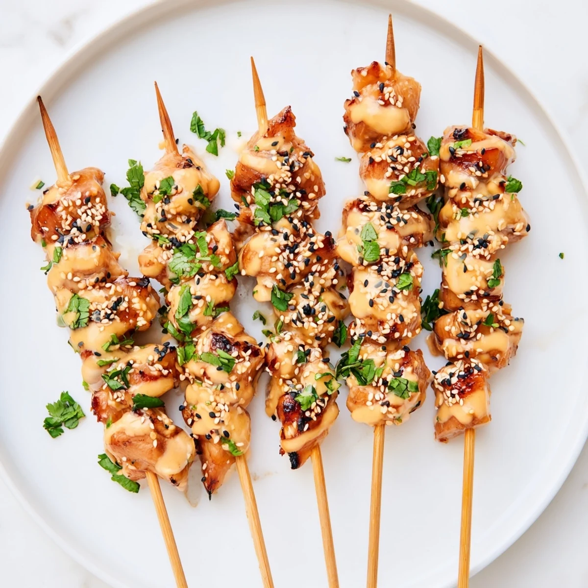 A close-up of grilled Bang Bang Chicken Skewers drizzled with spicy-sweet sauce, served with lime wedges for extra zest.