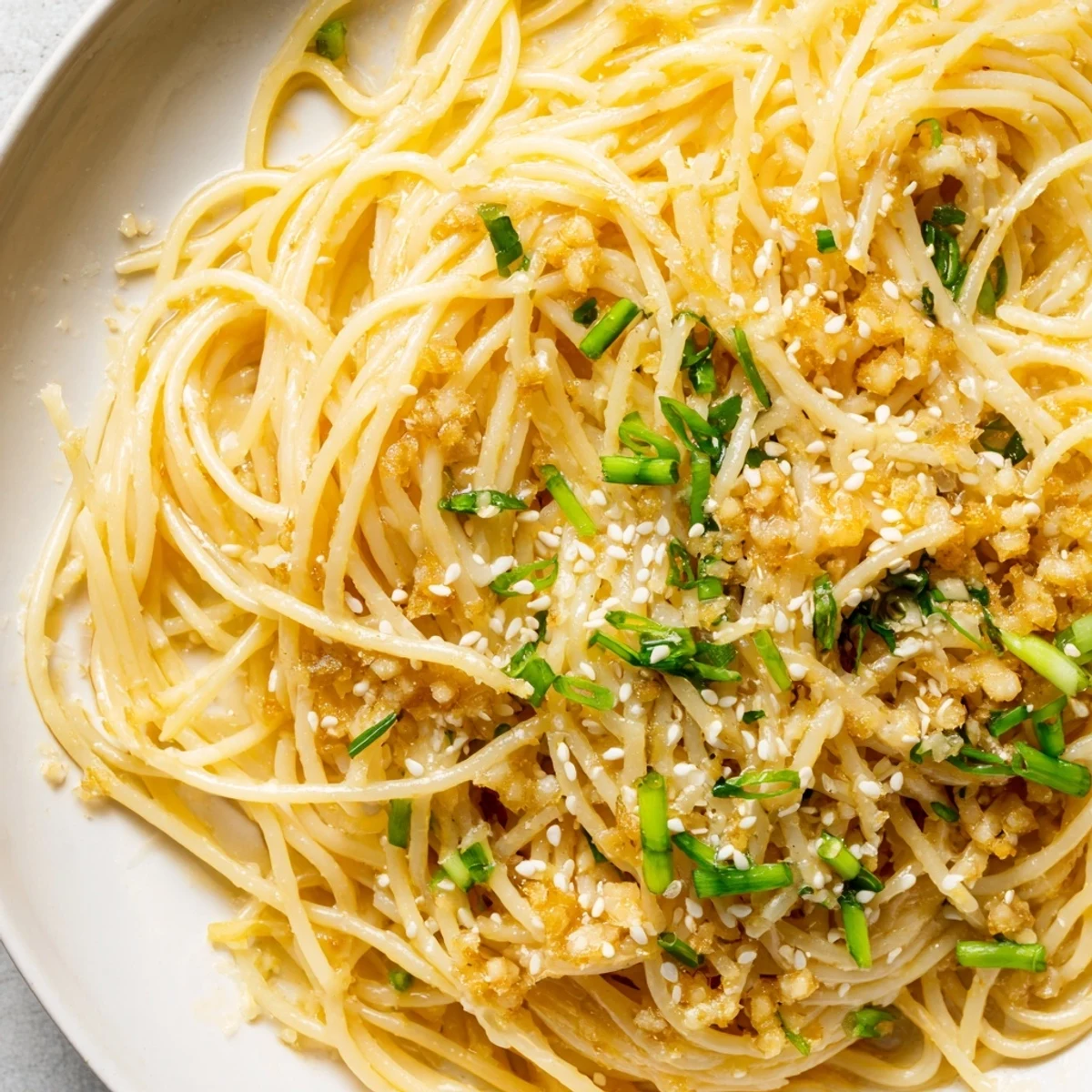 Steam rises from a plate of Garlic Noodles tossed with golden butter and minced garlic.