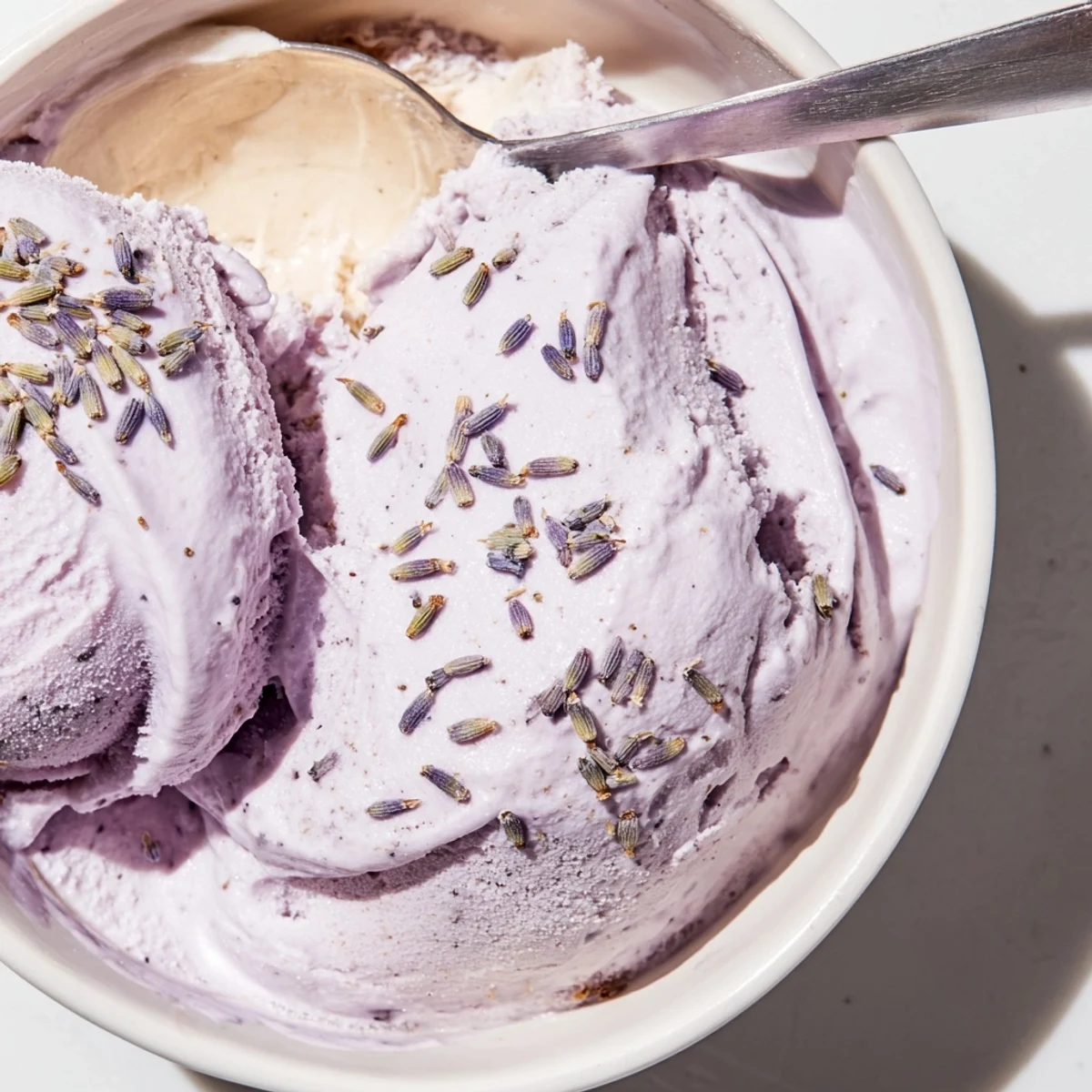 Lavender ice cream recipe in a chilled bowl, showing creamy texture and a sprinkle of dried lavender buds.