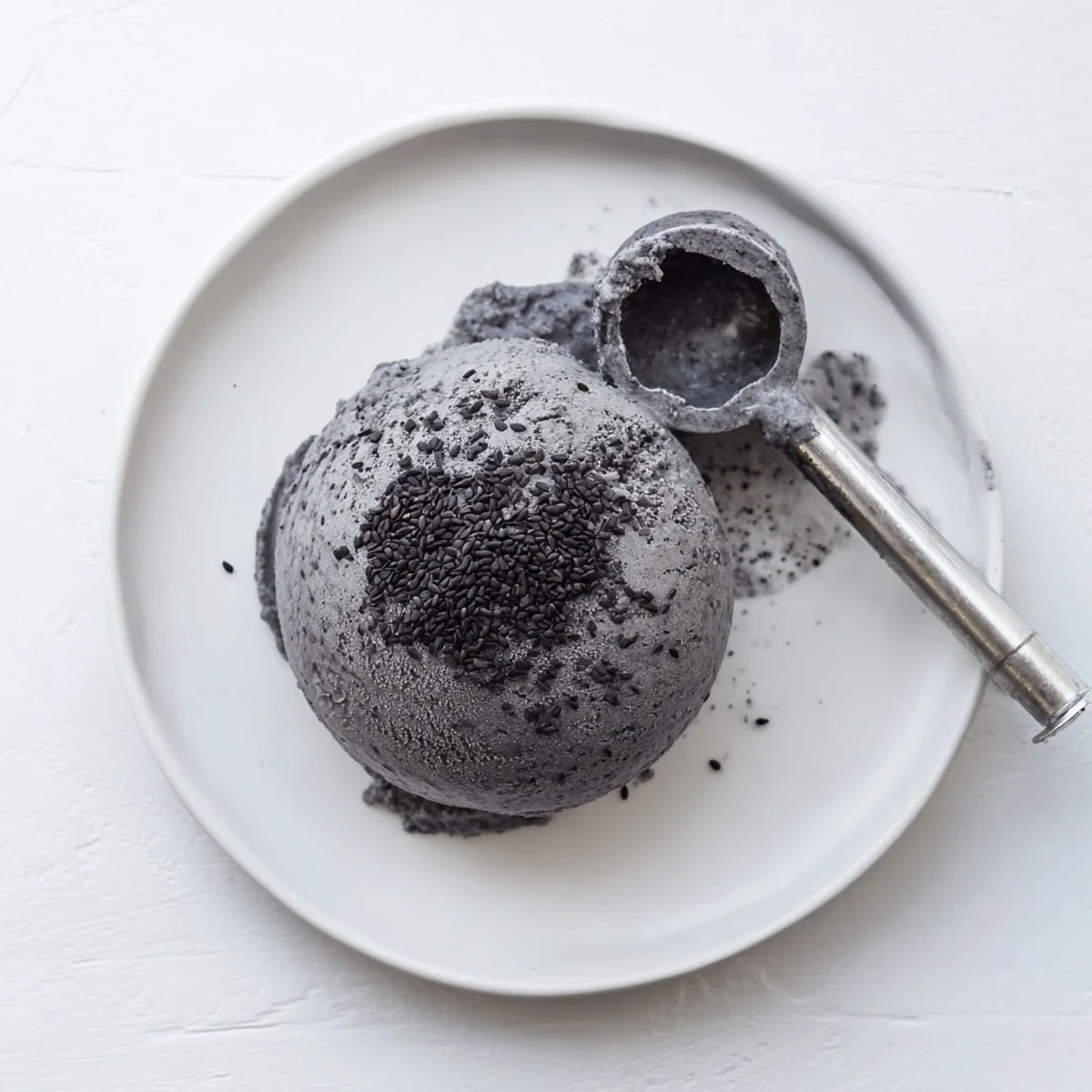 Creamy toasted black sesame ice cream in a bowl with a honey drizzle, topped with sesame seeds.