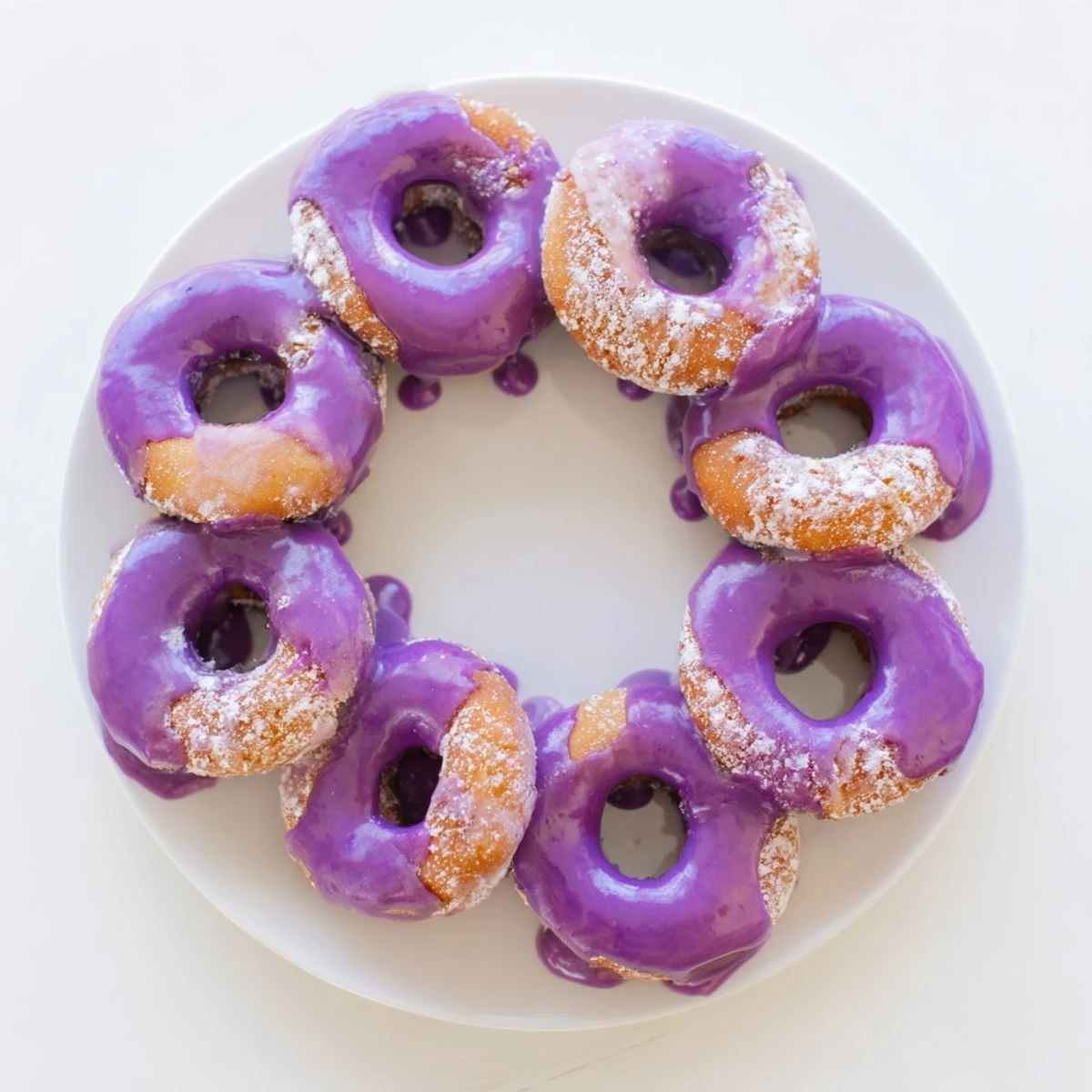 Glazed ube mochi donuts show a vibrant purple hue and glossy topping on a cooling rack.