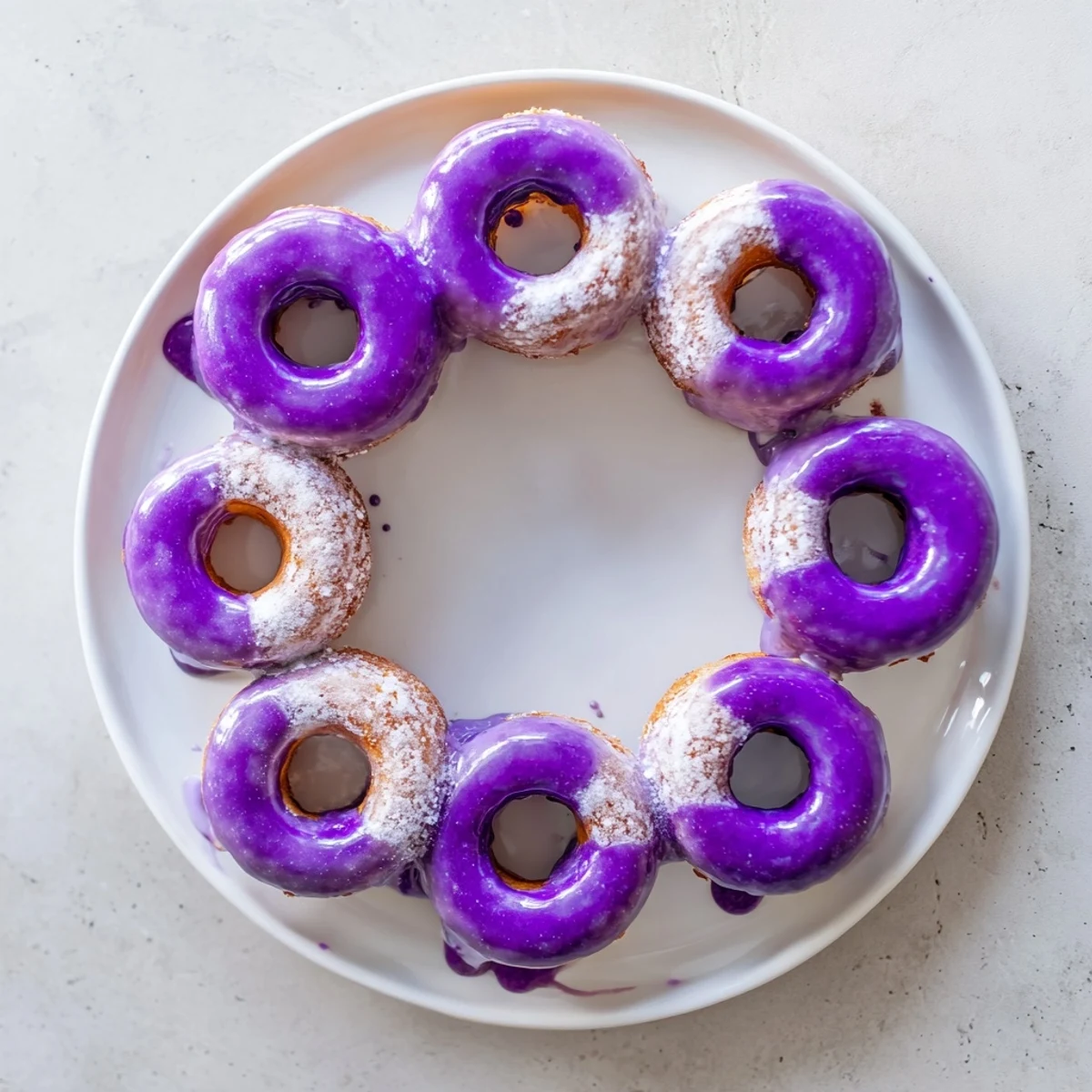Stacked ube mochi donuts with purple glaze are ready to serve with green tea.