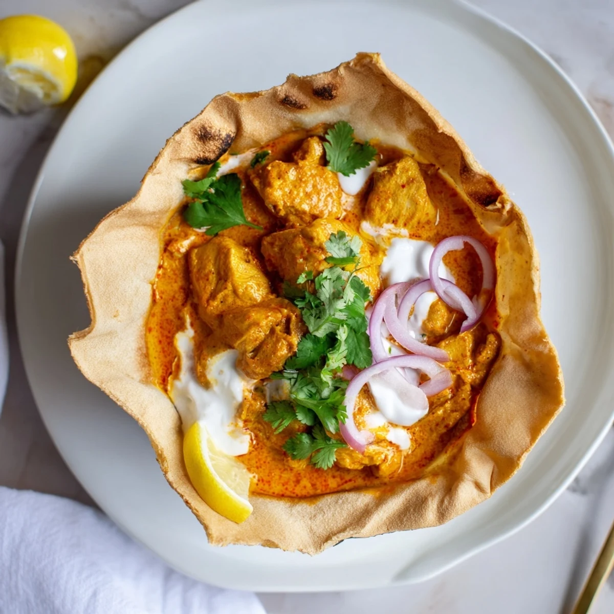 Warm, comforting Indian fusion meal featuring tender spiced chicken inside a baked roti shell, garnished with red onion and cilantro.