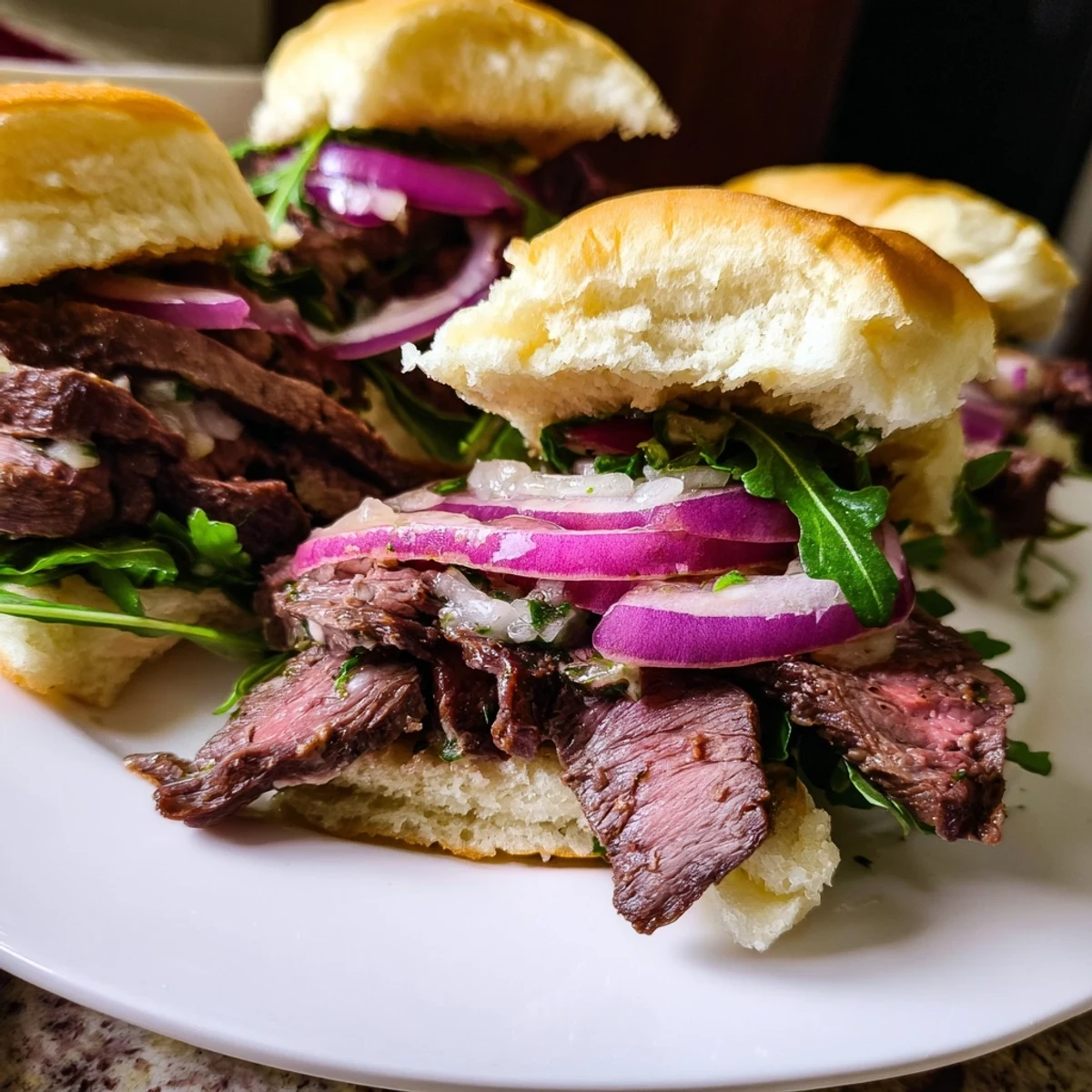Freshly grilled steak slices layered on toasted buns with vibrant arugula and red onion for Cowboy Butter Steak Sliders.