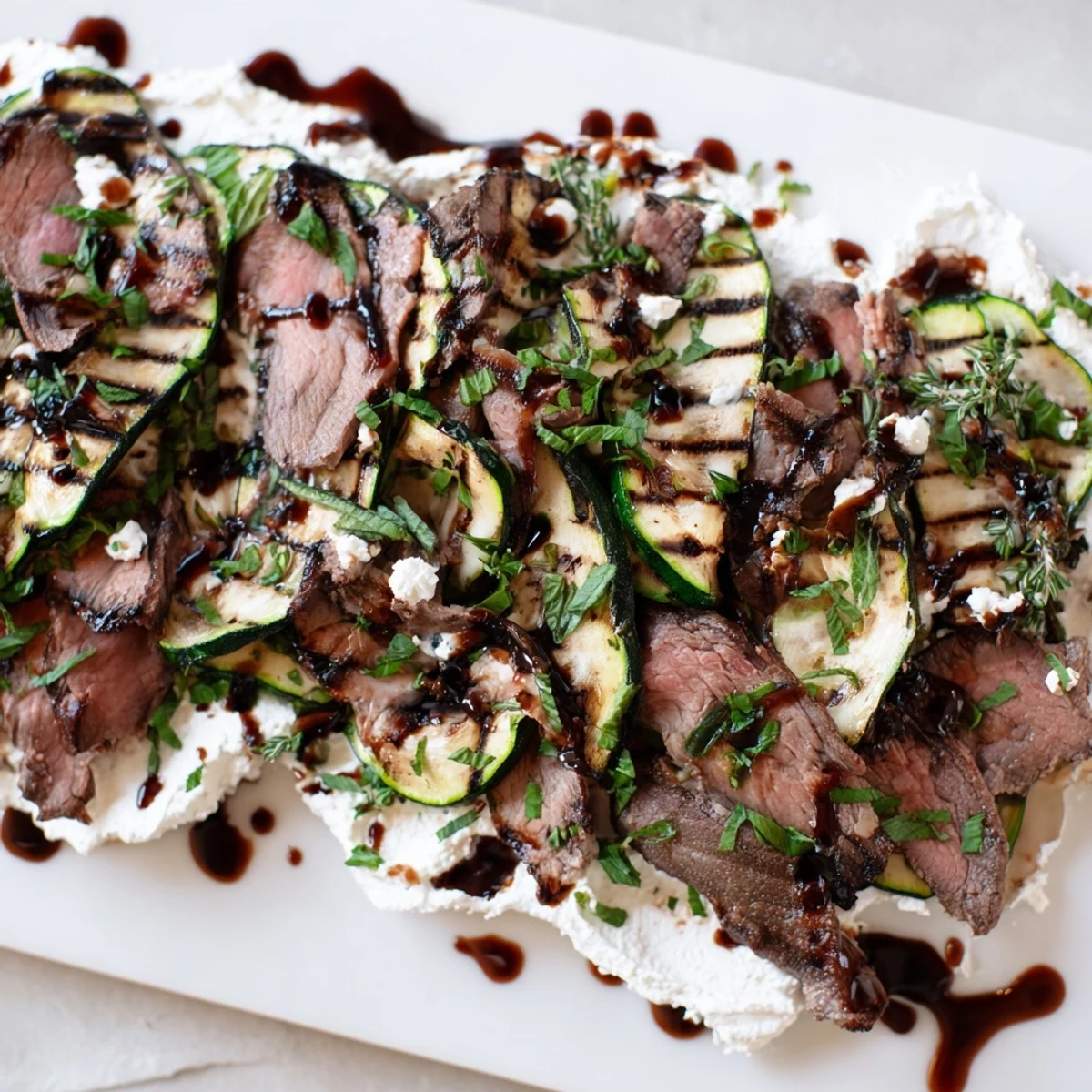Balsamic Flank Steak With Grilled Zucchini And Whipped Feta garnished with fresh mint for a summer dinner.