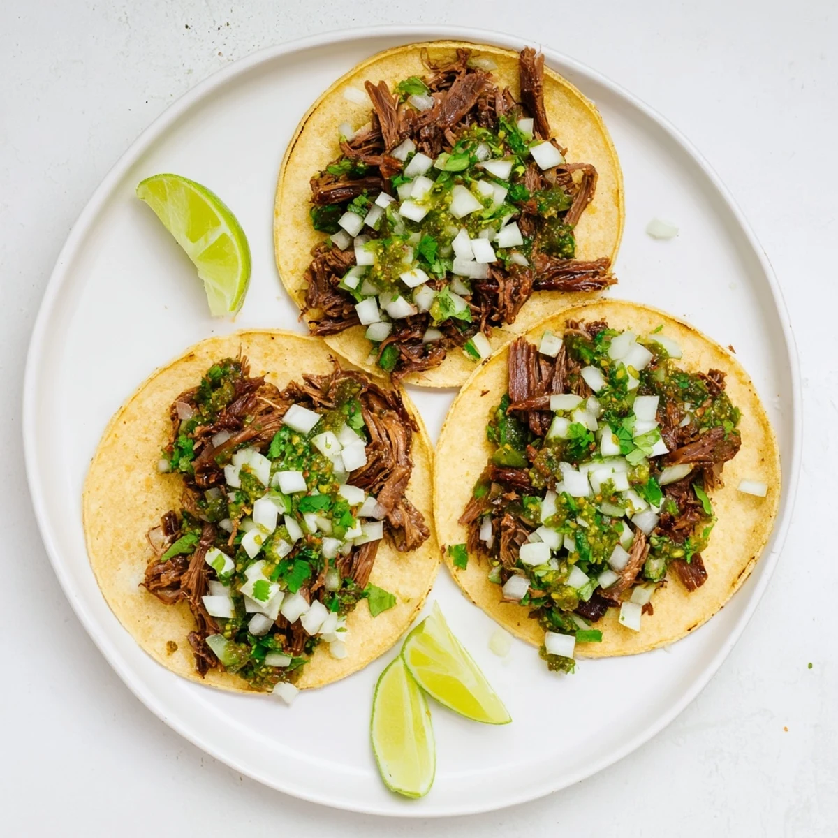 Steaming shredded beef cheeks nestled in warm corn tortillas, topped with cilantro and onion for Beef Cheek Tacos.
