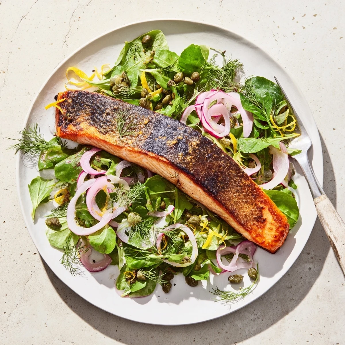 Golden-brown crispy skin Tasmanian Atlantic salmon fillets resting on a bed of lemony herb salad with dill and parsley.