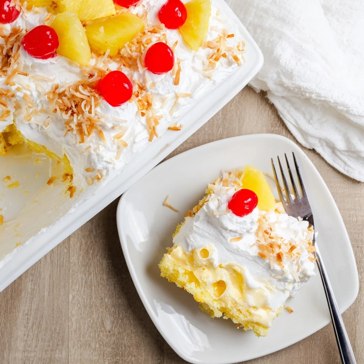 A slice of chilled Hawaiian Poke Cake showcases fluffy yellow cake soaked with sweetened condensed milk and coconut milk.