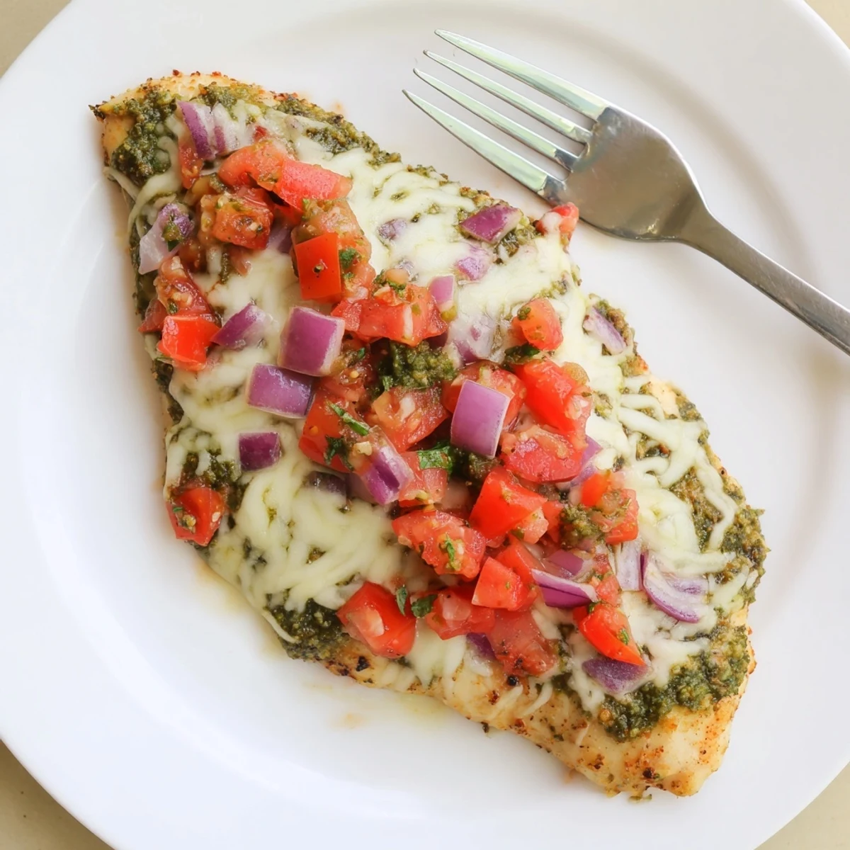 Close-up of Pesto Bruschetta Chicken showing tender chicken, basil pesto, and juicy tomato mixture.