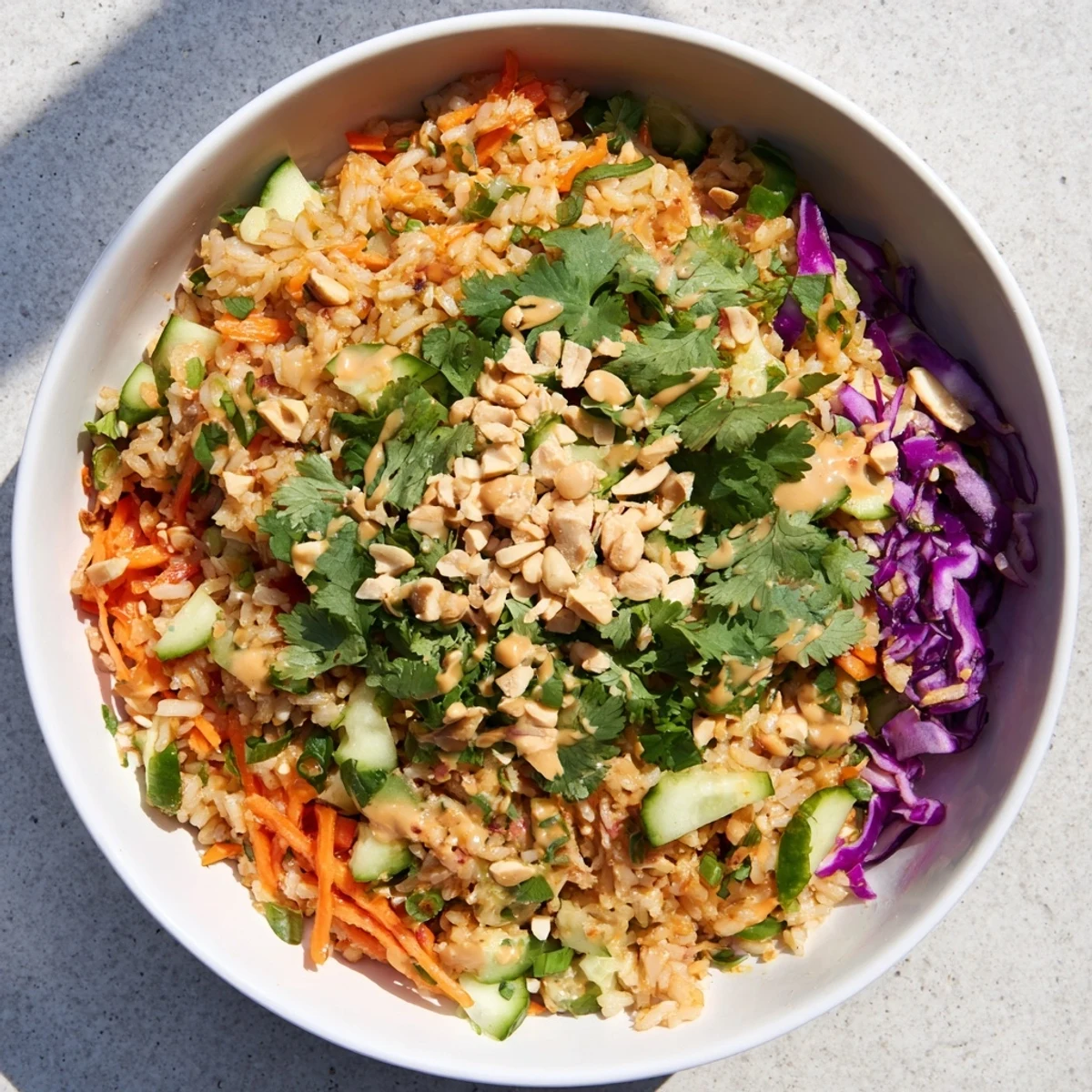 Close-up of crispy rice salad with peanut sesame dressing showcasing textured fried rice, carrots, and cucumber slices