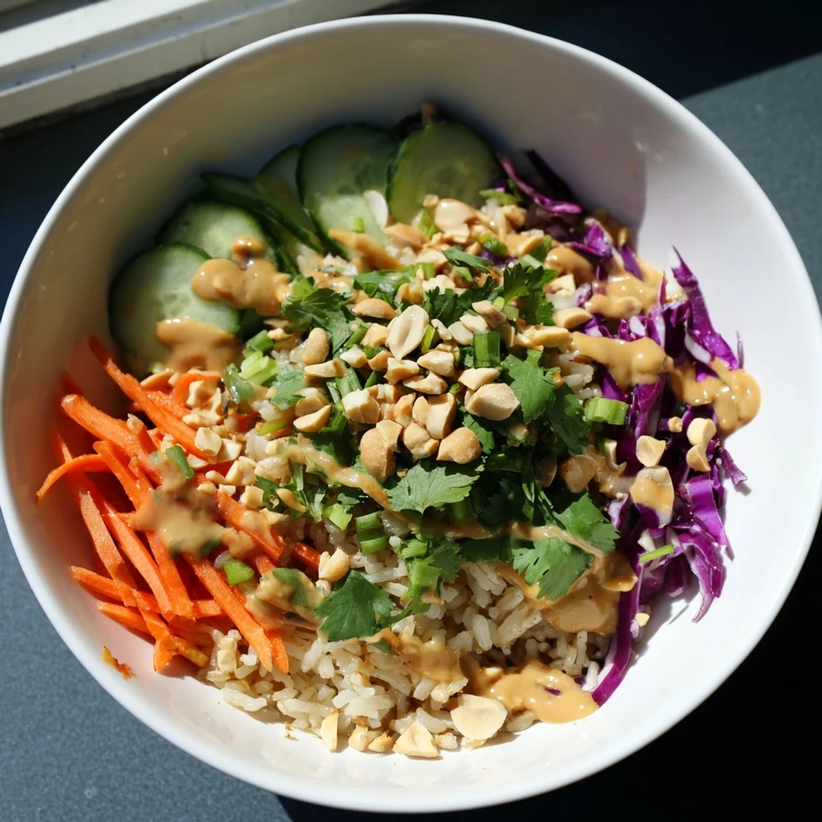 Bowl of Asian-inspired crispy rice salad topped with roasted peanuts, shredded vegetables, and creamy peanut dressing
