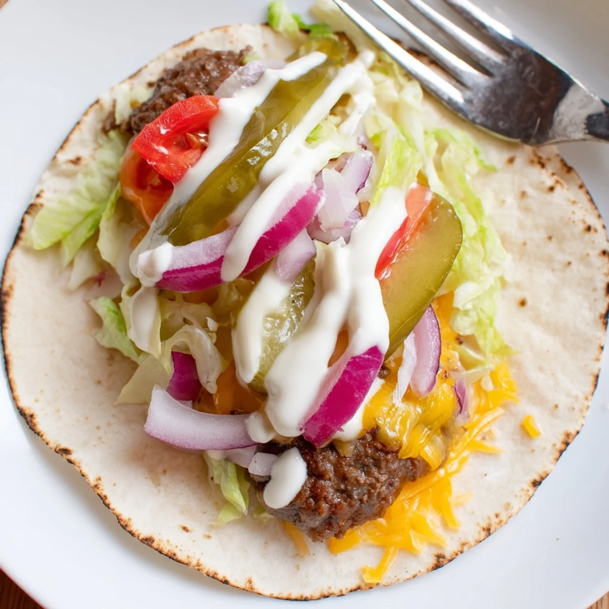 Juicy beef smash burger tacos topped with fresh lettuce tomato onion and tangy pickles