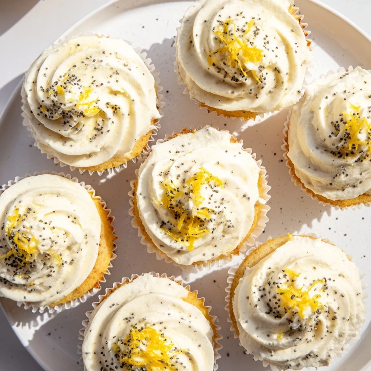 Golden lemon poppy seed cupcakes topped with swirls of creamy lemon cream cheese frosting