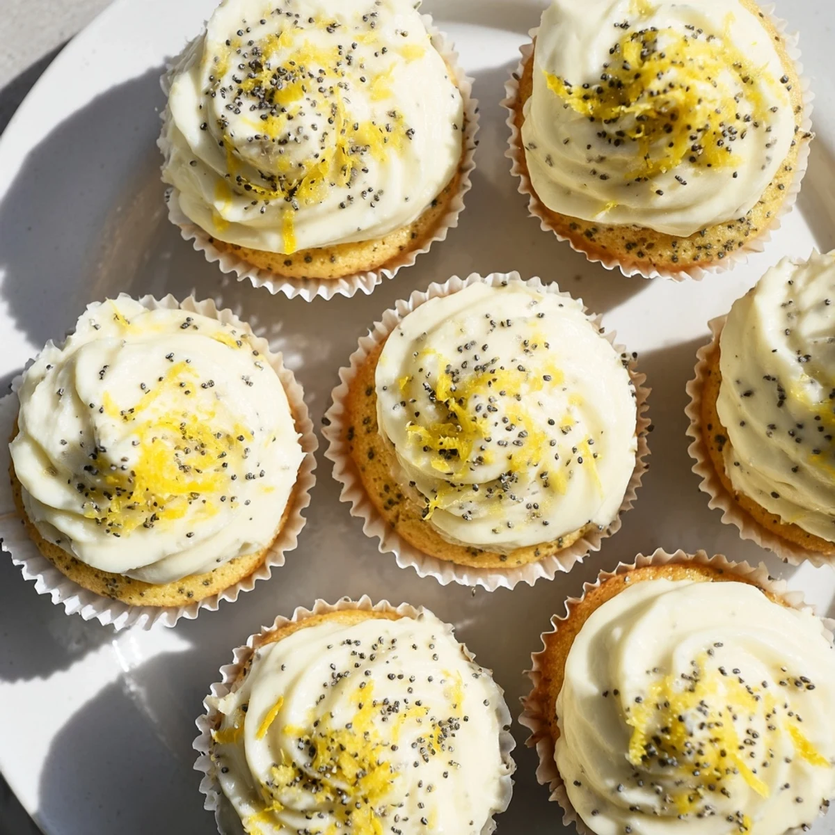 Freshly baked lemon poppy seed cupcakes cooling on a wire rack with generous frosting swirls