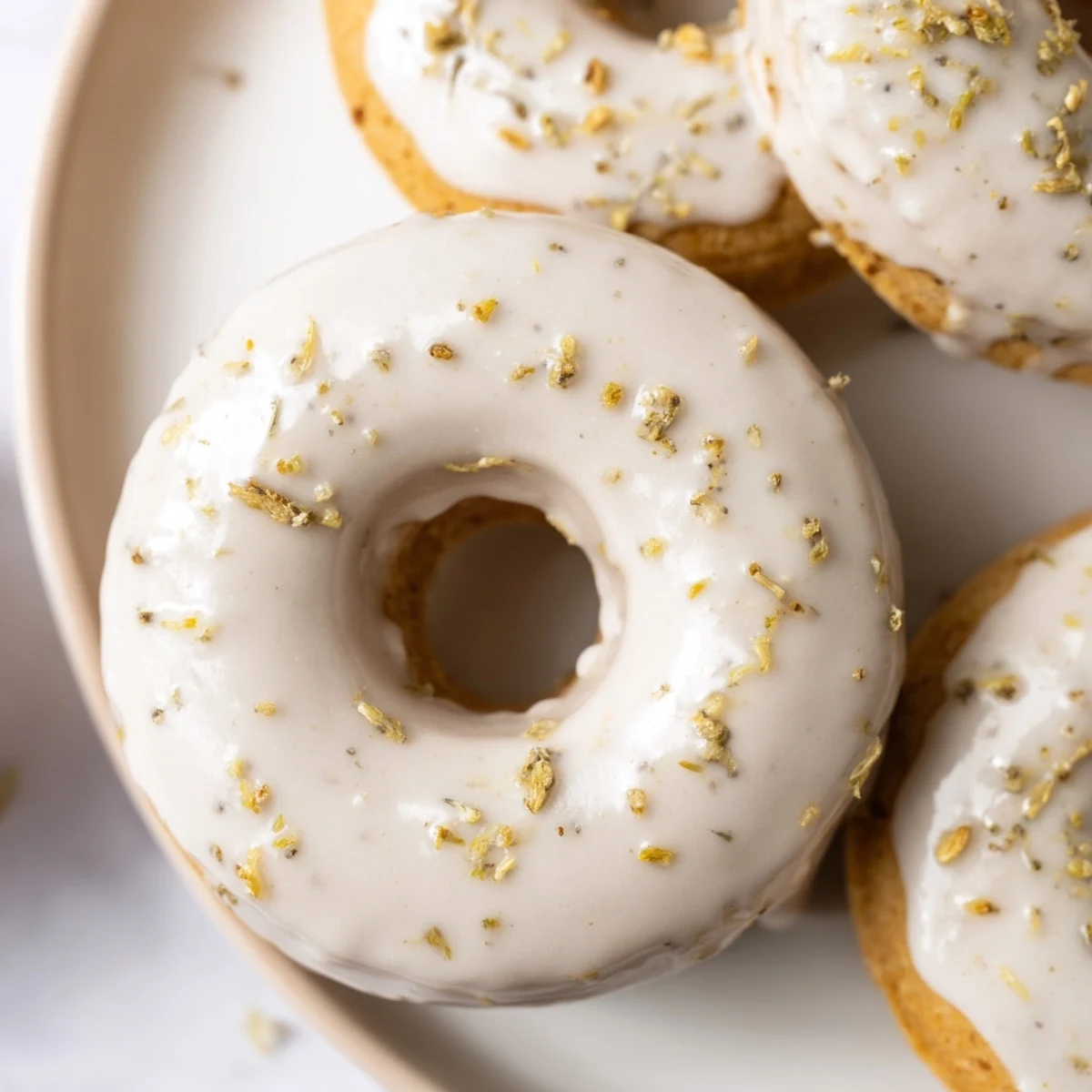 Golden glazed Earl Grey mochi donuts arranged on a wire cooling rack with tea-speckled frosting dripping down the chewy ring sides