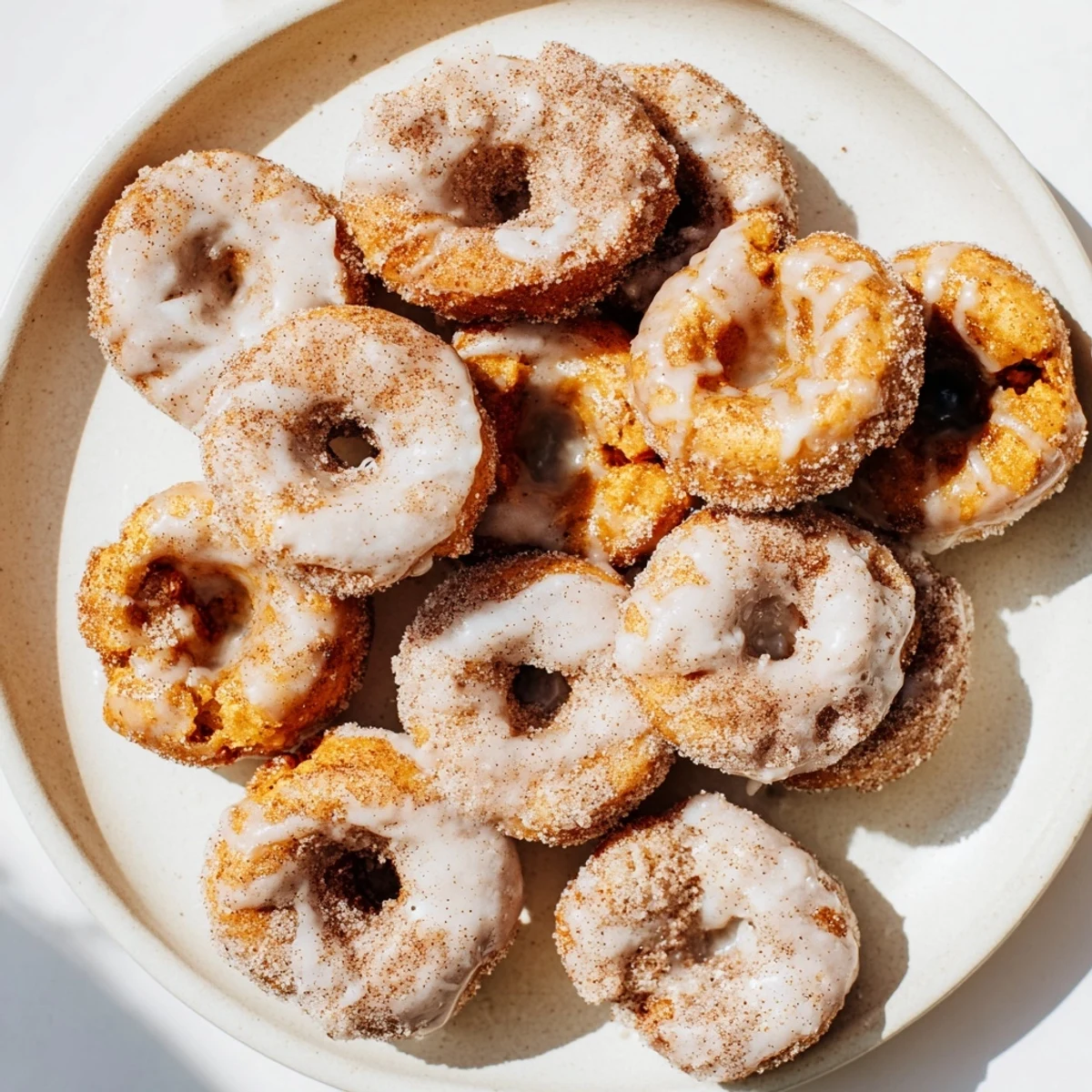 Golden pumpkin spice biscuit donuts coated in cinnamon sugar with sweet vanilla glaze drizzle