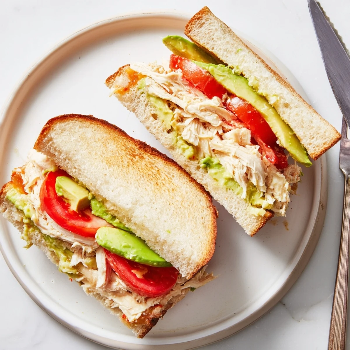 Golden grilled chicken avocado melt sandwich with melted cheese on toasted sourdough bread