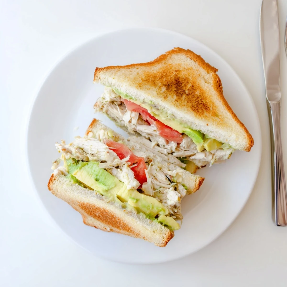 Sliced cross-section of warm chicken avocado melt sandwich revealing layers of cheese and vegetables