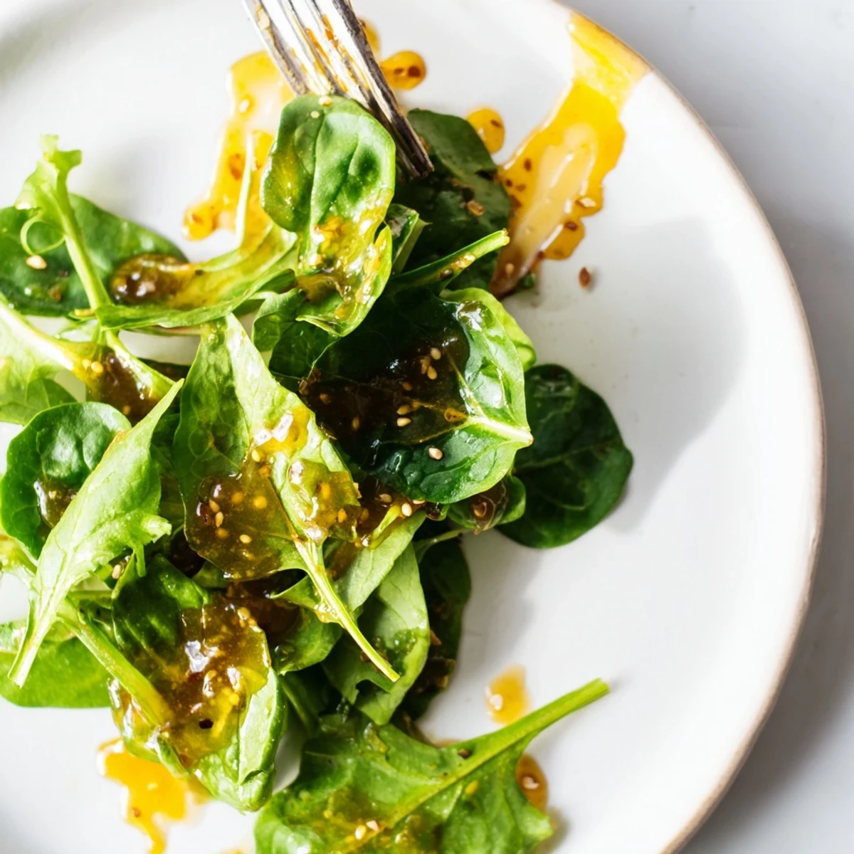 Golden honey lemon vinaigrette drizzled over fresh mixed greens in a white bowl