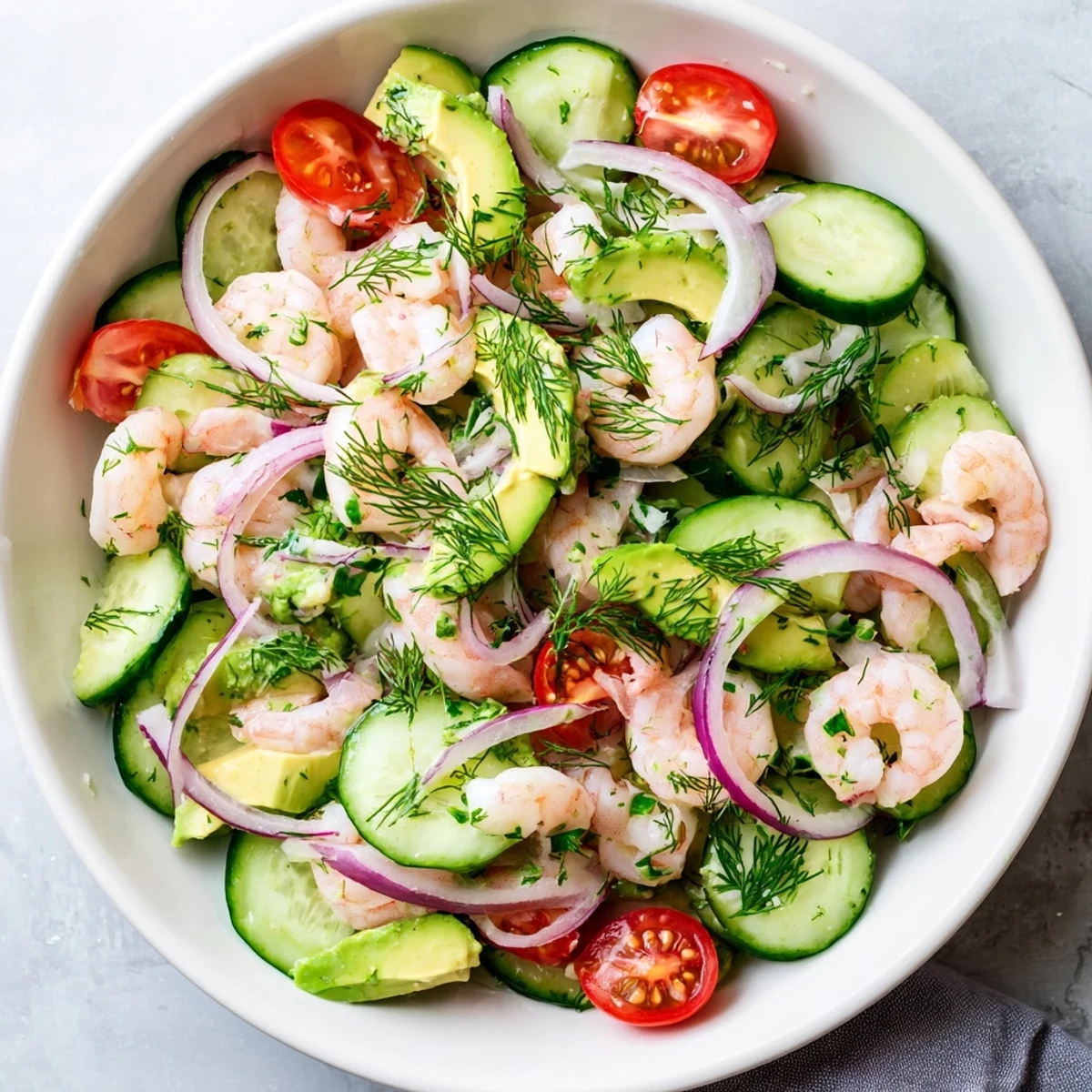 Light summer cucumber shrimp salad featuring juicy cherry tomatoes, creamy avocado, and cooked pink shrimp
