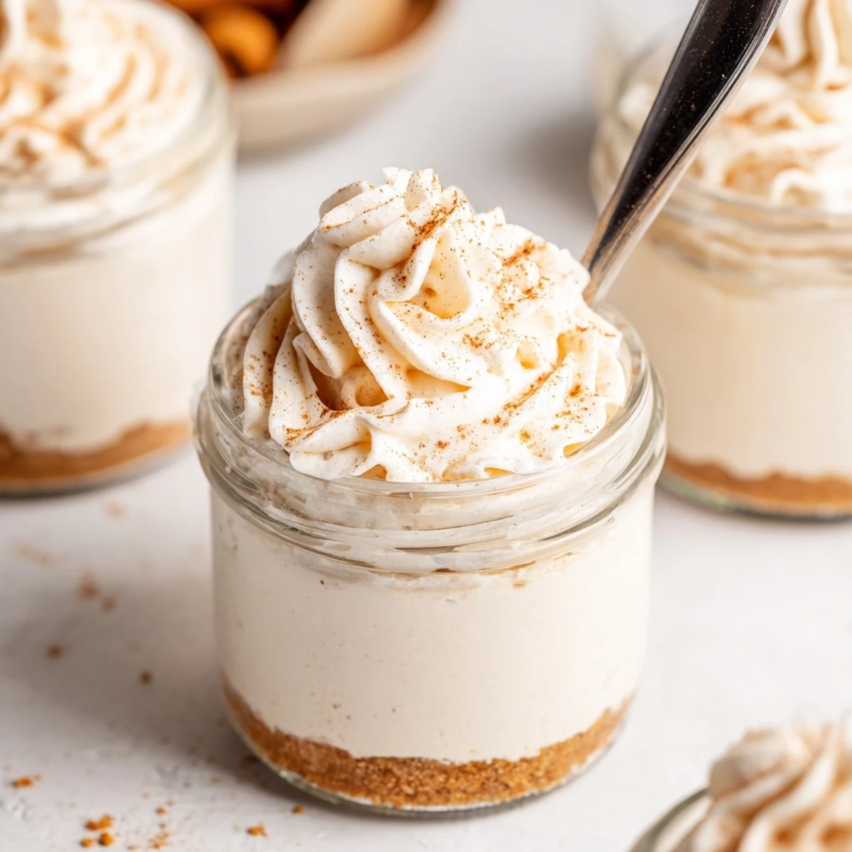 Individual no bake mini mason jar spiced cheesecakes with graham cracker crust and whipped cream topping