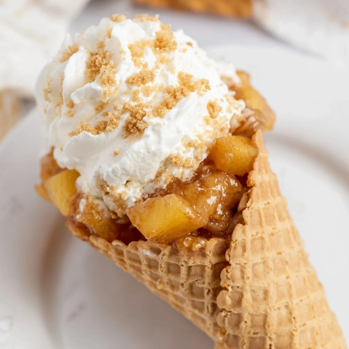Summer dessert showcasing layered peach cobbler cheesecake filling inside a crunchy waffle cone