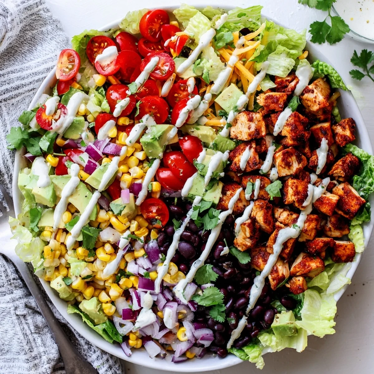 Protein-packed healthy BBQ chicken chopped salad featuring tender grilled barbecue chicken slices over a bed of vibrant vegetables including romaine, corn, black beans, avocado, and cheese