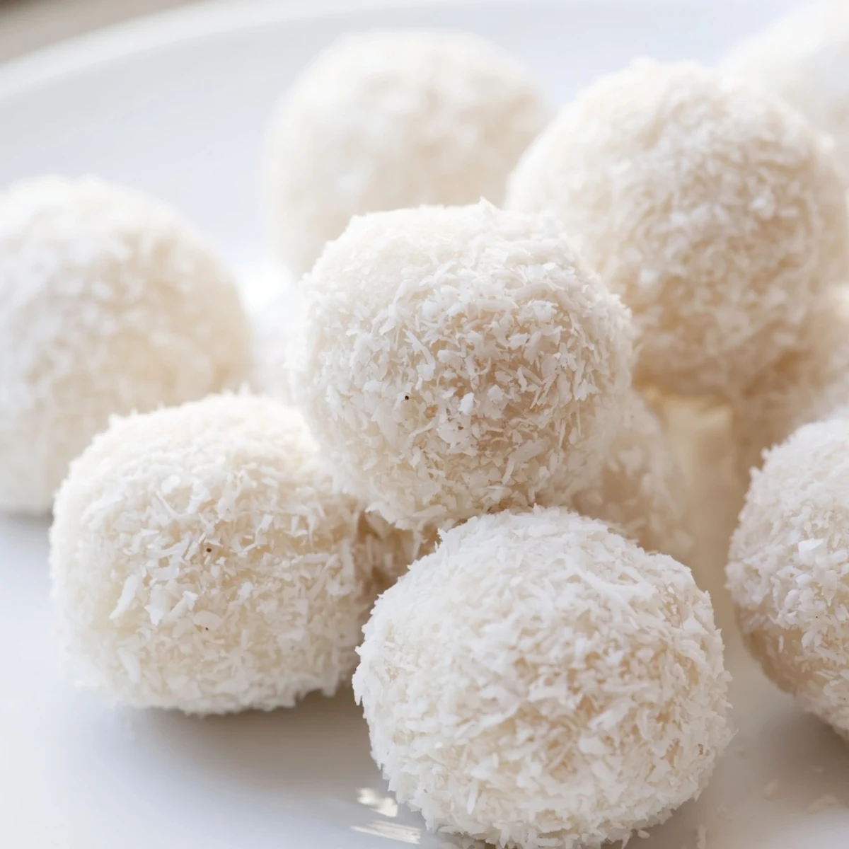 Soft white coconut tails rolled in shredded coconut arranged on parchment paper for Easter dessert