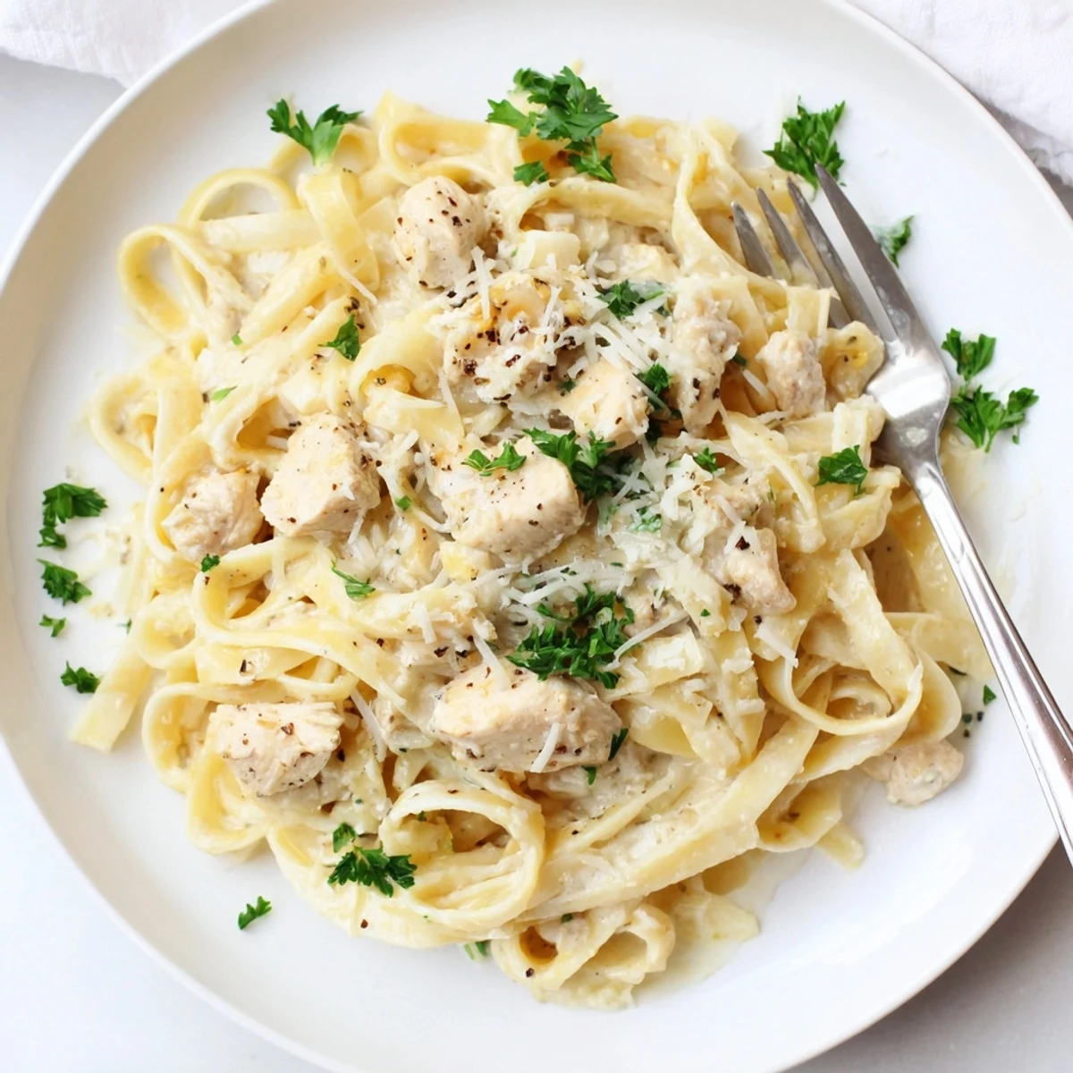 Creamy garlic Parmesan chicken pasta dish topped with fresh parsley and extra grated cheese.
