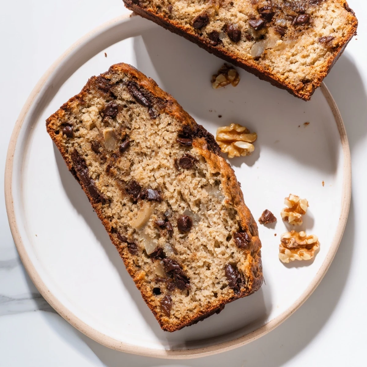 Golden brown keto banana bread loaf with a moist, tender crumb topped with chopped walnuts