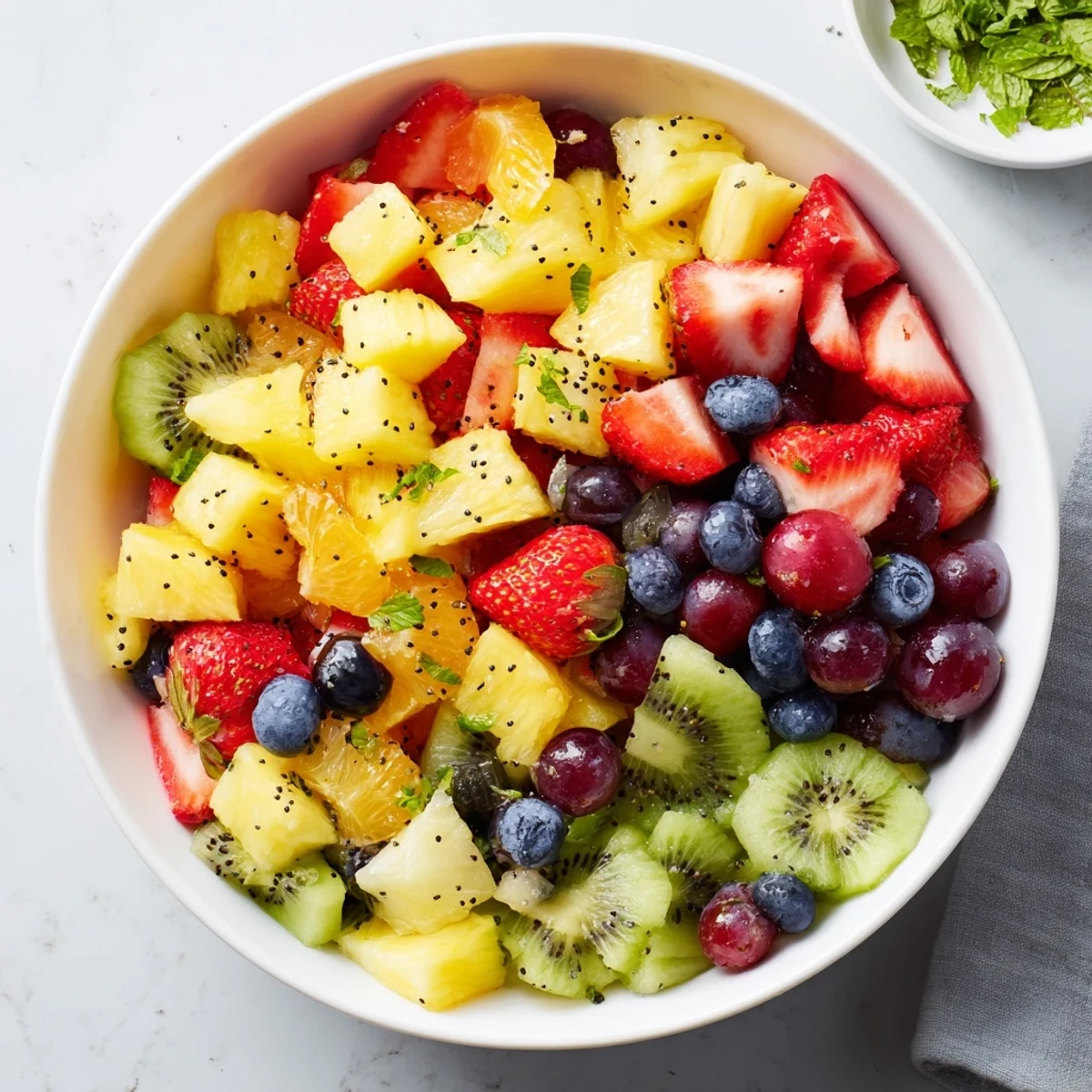 Colorful Easter fruit salad bowl overflowing with fresh strawberries, pineapple, grapes, and kiwi garnished with mint