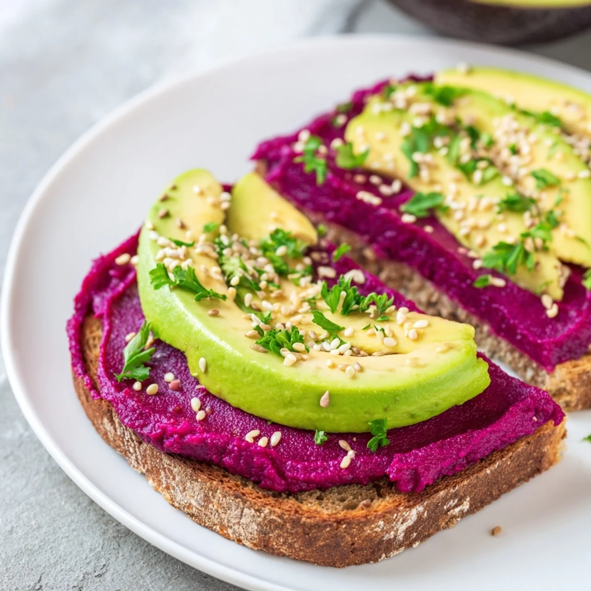 Golden avocado beet hummus toast layered with creamy hummus and ripe avocado slices on crispy whole grain bread garnished with fresh parsley